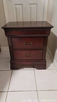 Front view showing two pull-out drawers with brass handles on a dark wood chest.