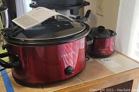 Red 6qt Crock-Pot with black handles and glass lid, showing dial and brand logo