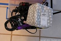 Photo showing a soft gray and white polka dot carrying case with multiple hair styling tools including curling irons and cords