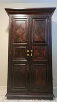 Full front view of solid oak wardrobe with two paneled doors and brass knobs.