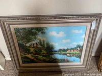 Full view of the framed painting featuring a rural landscape with house, trees, and river.