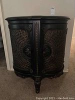 Front view of one carved wood cabinet showing curved lattice-pattern doors and medallion knob