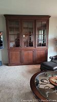 Full view of large wooden china cabinet with three glass paneled doors above and three wooden doors below, showing overall design and size.