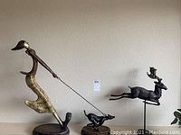 Overall view of metal lady-and-dog sculpture alongside deer candlestick