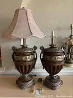 Pair of urn-style lamps on a table, one with a fabric shade, showing the overall design and condition of the lamps.