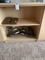 Wooden shelf with two metal plaques on upper shelf and two metal wall light fixtures on lower shelf, showing overall condition and arrangement.