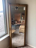 Full view of mirror leaning against wall showing overall shape and condition