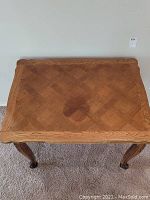Top view showing parquet pattern and carved edges of the wooden table top.