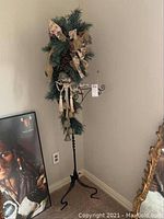 Full view of the decorative metal stand featuring greenery, tassels, and hanging bells.