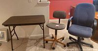 Photo of the folding table and two office chairs against a wall.