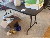 First image showing dark brown folding table with items on top and various kitchen utensils below.