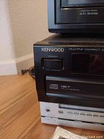 Close-up photo showing front left corner of Kenwood CD player with power button and Multiple Compact Disc Player label.