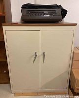 Full view of the beige metal locking cabinet topped with an IBM typewriter under a dust cover.
