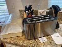 Stainless steel toaster with black trim, bread keeper and JA Henckels knife block set visible on kitchen counter.
