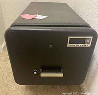 Front closed view of black Sentry file safe with handle, keyhole, and brand label.