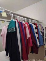 Clothing rack with multiple women's tops and sweaters in various colors and styles.