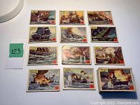 Display of multiple trading cards from the set showing colorful depictions of ships at sea and in battle, cards numbered 1 to 12 visible, with the cards laid out on a white surface.