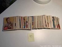 Full laid-out stack of approximately 88 vintage celebrity trading cards from the 1960s, showing cards face-up with various color photos and names.