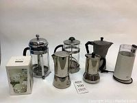 Full view of 7 assorted coffee and tea makers including Bodum French presses, Italian espresso makers, coffee grinder, Kati Tea Forté tea brewer, and milk frother