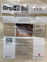 Close-up photo of the product label showing brand Grip-It, model Ultra Stop, size 8' x 11' with usage information for non-slip rug pad for hard floors.