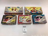 Top-down view of five boxed Corgi die cast collectible cars with various British comic themes including Beano, Dandy, Adventure, and The Hotspur.