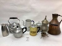 Photo showing the entire set of 8 vintage metal teapots and vessels including copper pitcher, aluminum and enamel pieces.