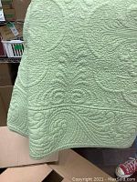 Close-up of the green quilted fabric showing detailed quilting patterns and texture