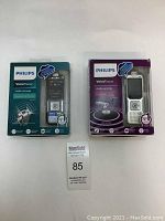 Two Philips Voice Tracer audio recorders in boxes, green box for new and purple box for used/untested, displayed side by side.