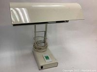 Full view of therapy light lamp showing the light housing, vertical frame, base, and coiled power cord.