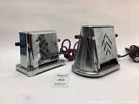 Two vintage chrome toasters on white background shown from front and side angles. One toaster is rectangular with diamond quilted pattern, the other has rounded base with chevron cut-outs.