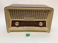 Front view of vintage radio featuring cream-colored speaker grill and front controls.