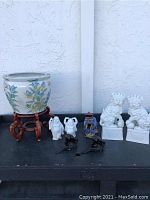 Front view of large painted ceramic vase bowl on wooden stand with various small figurines including lions, monks, man, and monkeys.