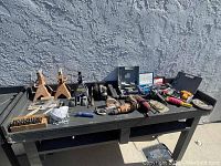 Wide view of all items arranged on black bench showing jackstands, tools, and accessories.