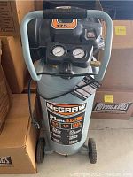 Front view of McGraw air compressor showing control panel with two pressure gauges and carrying handle.