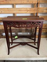 Front view of one wooden sofa table showing carved apron and angled legs.