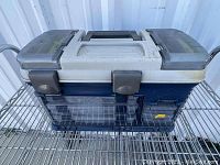 Closed Plano tackle box in blue and gray with secure black latches and a central handle, showing slight dust and usage marks.