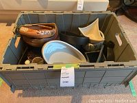 Gray plastic crate filled with various ceramic trays, bowls, and flower frogs, displaying assortment of colors and shapes.