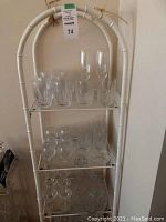 White metal stand with three glass shelves displaying entire collection
