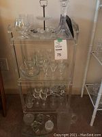 Clear glasshouse multi-tier cabinet filled with various glassware and crystal items