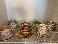 Front view of seven bone china cup and saucer sets arranged on wire shelf