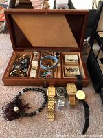 Open wooden jewelry box with watches and beaded necklace in front