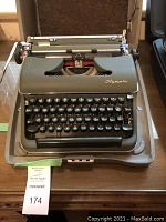 Front view of the green Olympia typewriter in its open hard case showing keyboard and logo.