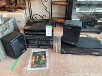 Full view of Pulser stereo system with turntable, dual cassette decks, two Newave speakers, Toshiba DVD player, assorted CDs and DVDs in front including a DVD movie in plastic