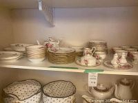 Overview of shelf showing teapot, serving dishes, plates, cups, saucers, creamer, sugar bowl and salt & pepper shakers