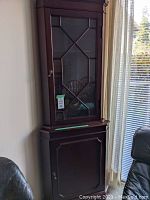 Full view of the solid wood corner cabinet, showing the dark wood finish, glass door on the top half, and solid door on the bottom half.
