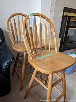 Two solid wood bar stools positioned side by side showing the full height and design