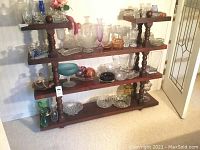 Full view of wood display shelf loaded with glass items (not included in lot) showing construction and design