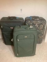 Three suitcases grouped together: green Jaguar suitcase, black Atlantic suitcase, and floral Air Canada suitcase