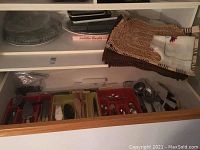 Drawer containing trays with various cream-handled utensils and silver plated spoons.
