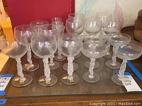 Wide view of assortment of Castle Art Crystal glasses with twisted frosted stems on glass surface